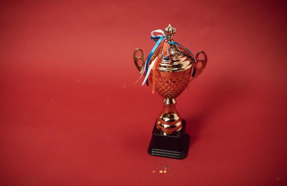 a trophy with tied ribbons on red background