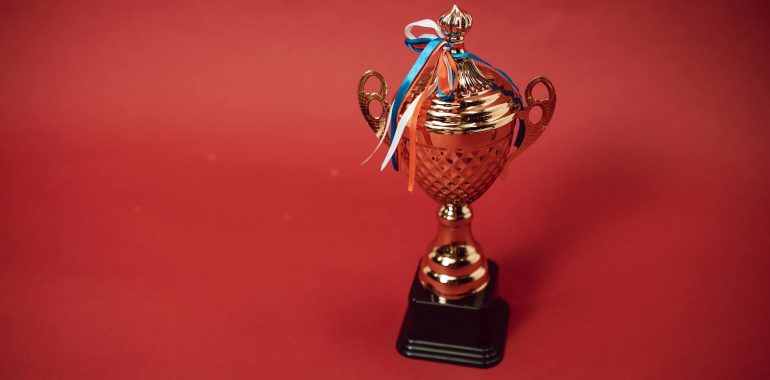a trophy with tied ribbons on red background